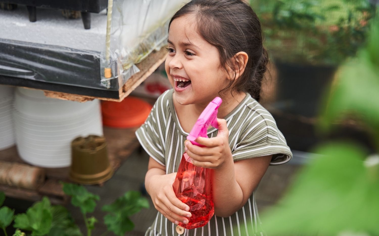 Child in the garden saving water with a spray bottle
