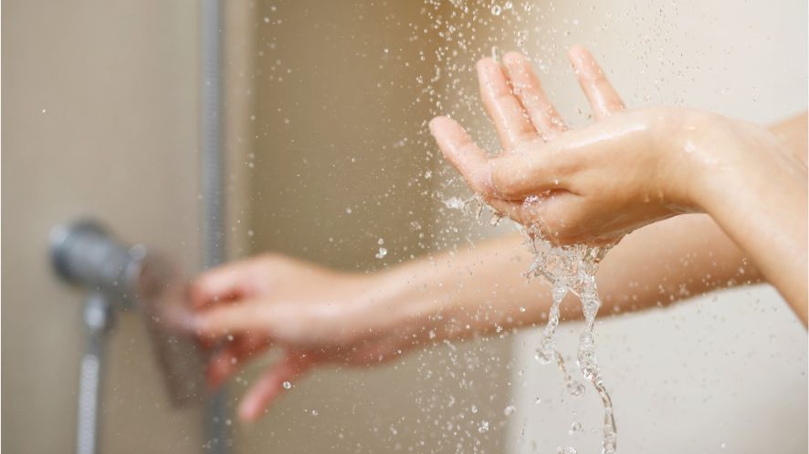 Pair of hands underneath running shower